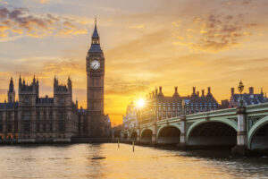 Big Ben and the Palace of Westminster at sunset, viewed from Westminster Bridge in London. The sky is a mix of warm tones, reflecting on the Thames River, while the historic architecture is illuminated by soft lighting. As you can see, the city is fascinating and you'll find plenty of things to do in London with teenagers if you're travelling with family.