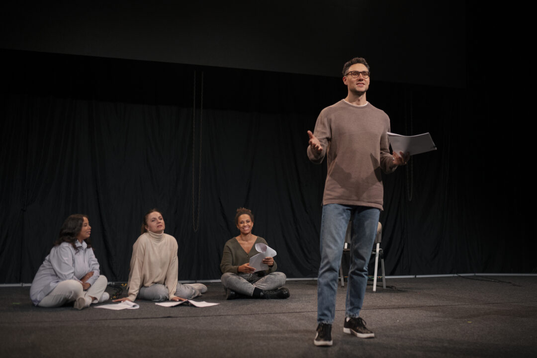 A moment from a theater class, capturing students engaged in performing arts activities on stage. They appear expressive and focused on stage.